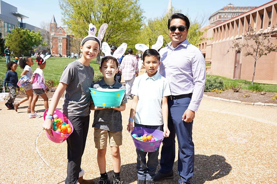 A family poses for a photo on campus during the Easter Egg Hunt.