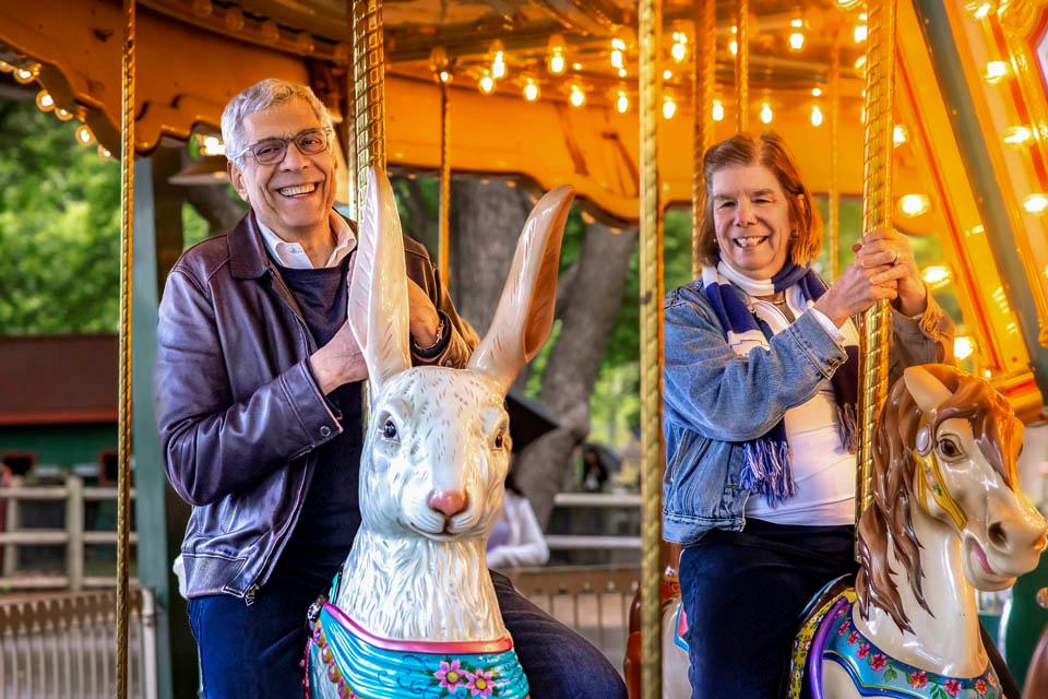 President Fred P. Pestello, Ph.D., and First Lady Fran Pestello, Ph.D., ride the carousel during a celebration for the Pestellos with the SLU community at Grant’s Farm on April 27, 2025. Photo by Sarah Conroy.