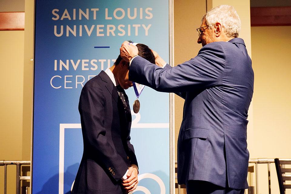 An honoree receives recognition on stage at the Investiture Ceremony. 