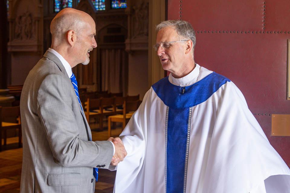 President Edward Feser, left, shakes hands with Very Rev. Thomas P. Greene, S.J..