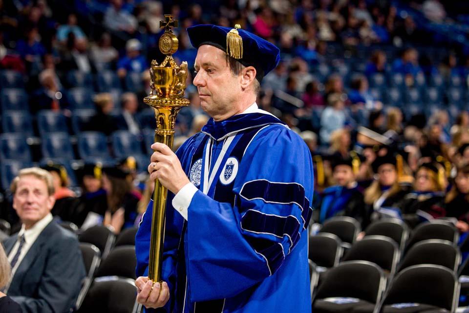 Eric Engler, chairman of the SLU Board of Trustee, carries in the University mace. Photo by Sarah Conroy.