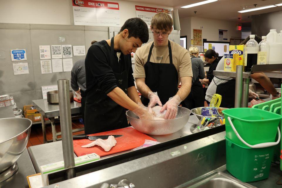 Volunteers at Campus Kitchen cut a turkey into smaller pieces for cooking. Photo by Maggie Rotermund.