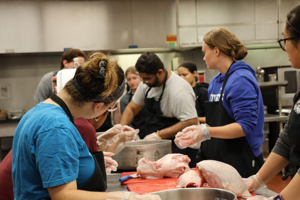 Volunteers at Campus Kitchen listen to team leader Path Patel, center, explain how to cut up a turkey. Photo by Maggie Rotermund.