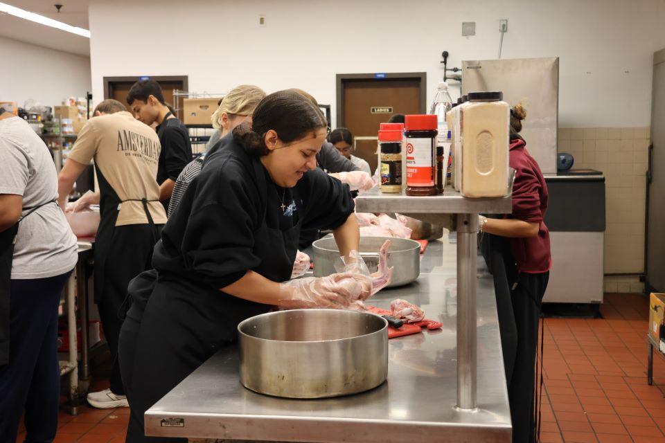 Volunteers at Campus Kitchen cut a turkey into smaller pieces for cooking during TurkeyPalooza 2025. Photo by Maggie Rotermund.