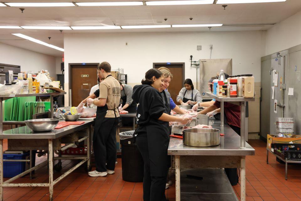 Volunteers at Campus Kitchen cut a turkey into smaller pieces for cooking. Photo by Maggie Rotermund.