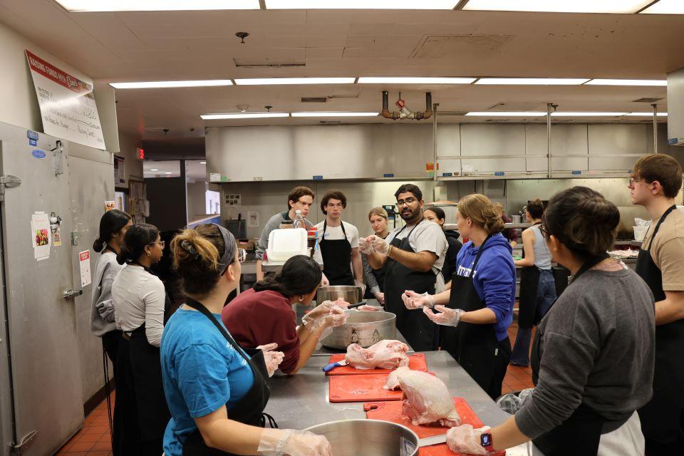 Volunteers at Campus Kitchen listen to team leader Path Patel, center, explain how to cut up a turkey. Photo by Maggie Rotermund.