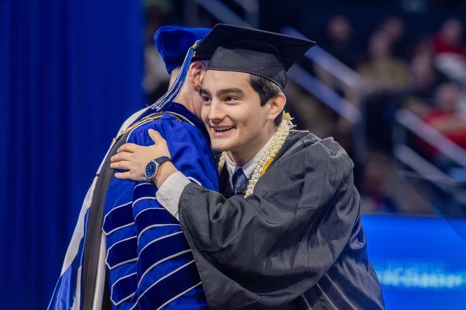 A graduate embraces President Edward Feser, Ph.D. Photo by Sarah Conroy.