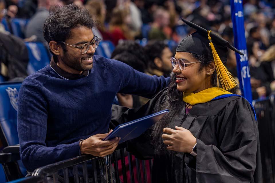 A graduate stops to hug her brother after receiving her diploma during Midyear Commencement on Saturday, Dec. 13, 2025. Photo by Sarah Conroy.