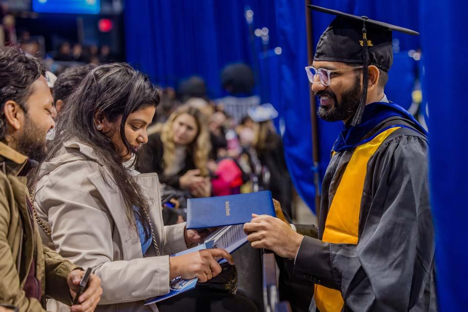 A graduate shares his diploma with family during Midyear Commencement on Dec. 13, 2025. Photo by Sarah Conroy.