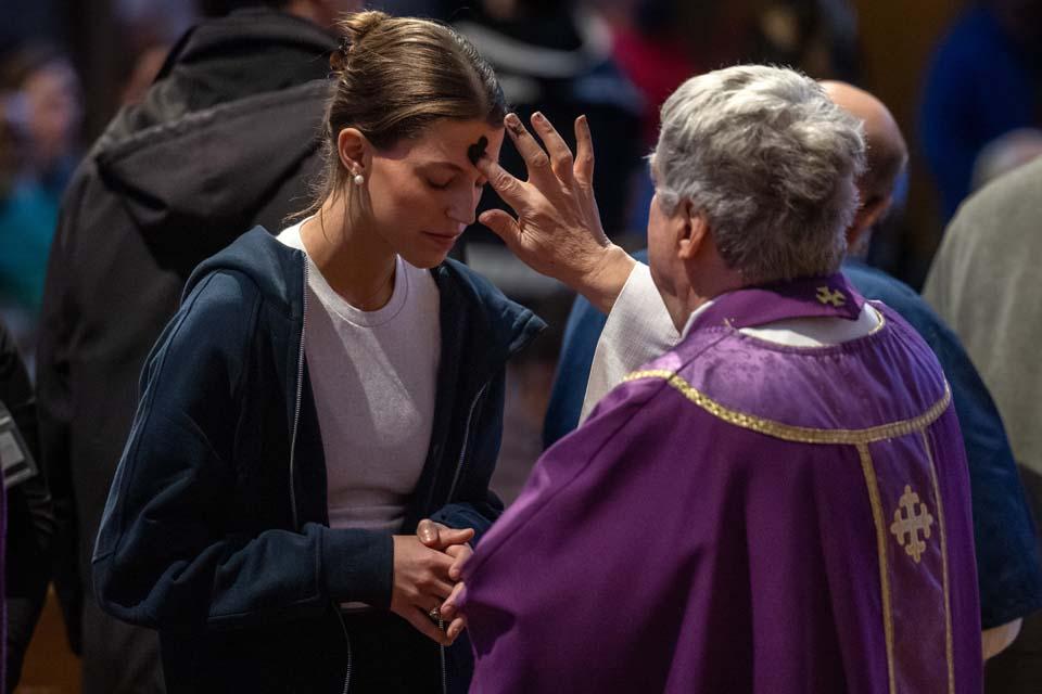 a priest applies ashes to a woman