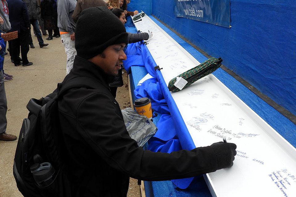 A student writes a message on the topping-out beam. Photo by Amelia Flood