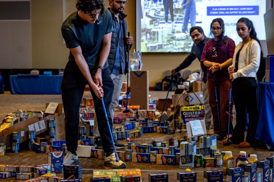 Members of the SLU community play miniature golf on a course constructed from shelf-stable grocery items at Golf and Give, an Innovation Challenge to benefit Billiken Bounty, on February 24, 2026. Photo by Sarah Conroy.