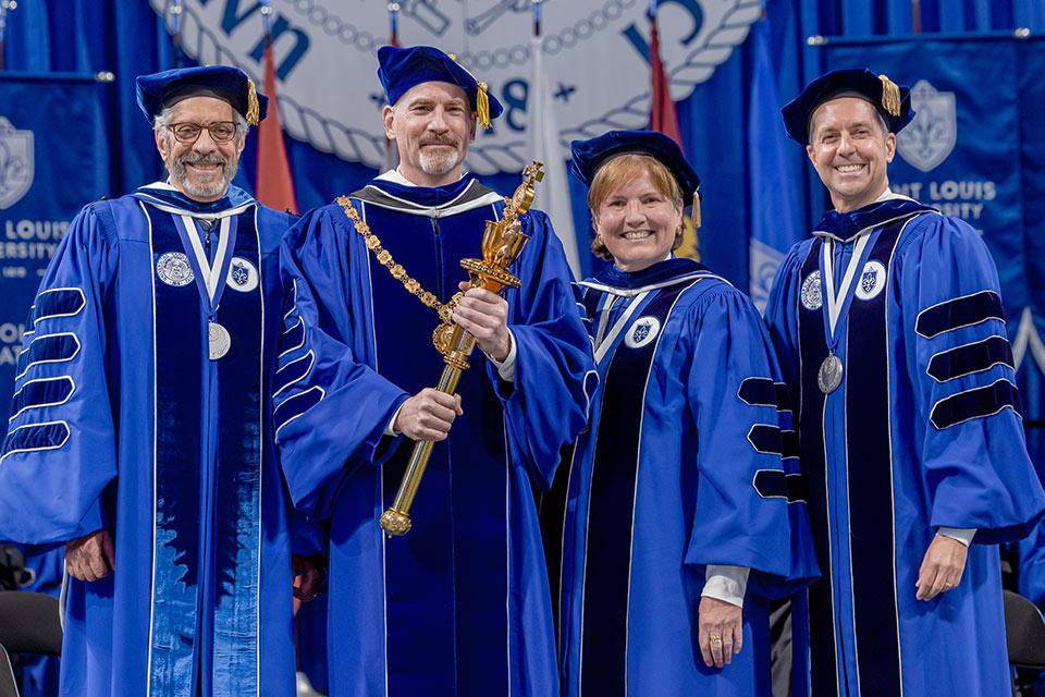 During the ceremony, Feser received the official symbols of the University: the chain of office from Marian “Bo” Mehan (VSN ’74, Law ’82) (second from right), vice chair of the board of trustees, and the University mace from President Emeritus Dr. Fred P. Pestello (left). Eric Engler (right), chairman of the board, formally installed Feser as president.