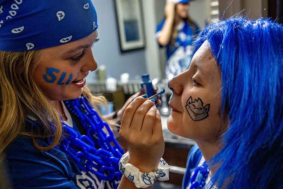 Students paint their faces before the first round game of the NCAA Tournament in Buffalo, NY on March 19, 2026. Photo by Sarah Conroy.

