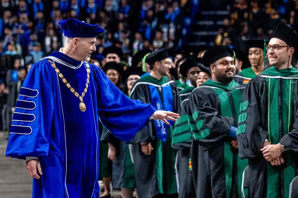 President Edward Feser, Ph.D., greets graduates from the School of Medicine as he processes into commencement on May 16, 2026. Photo by Sarah Conroy.