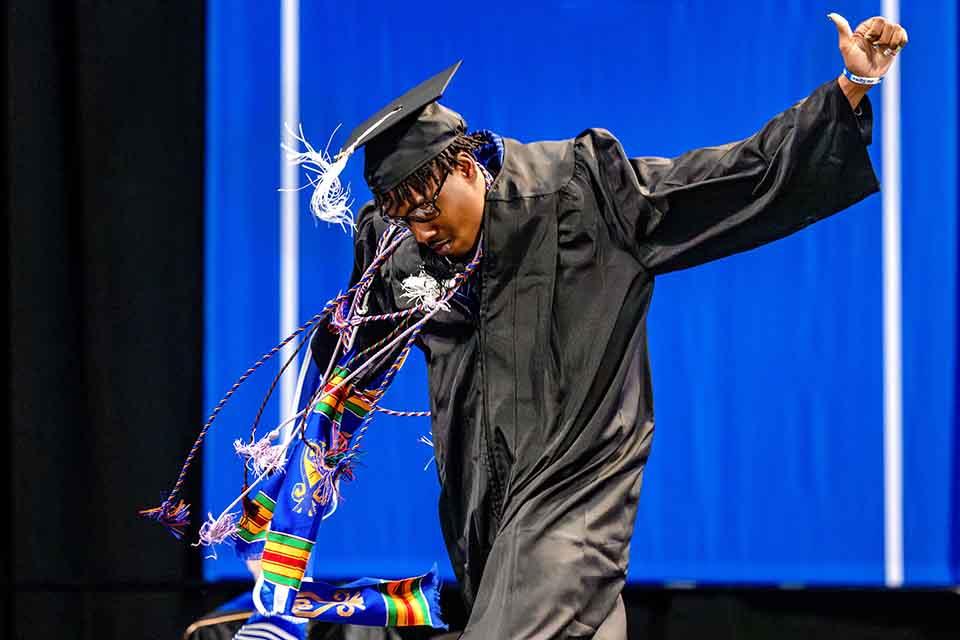 Russell Hooker Jr. dances across the stage to receive his diploma during the College of Arts and Sciences precommencement ceremony on May 14, 2026. Photo by Sarah Conroy. 

