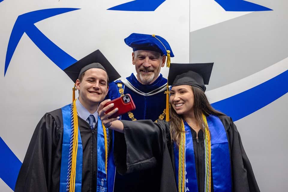President Edward Feser, Ph.D., takes selfies with graduates after commencement on May 16, 2026. Photo by Sarah Conroy.