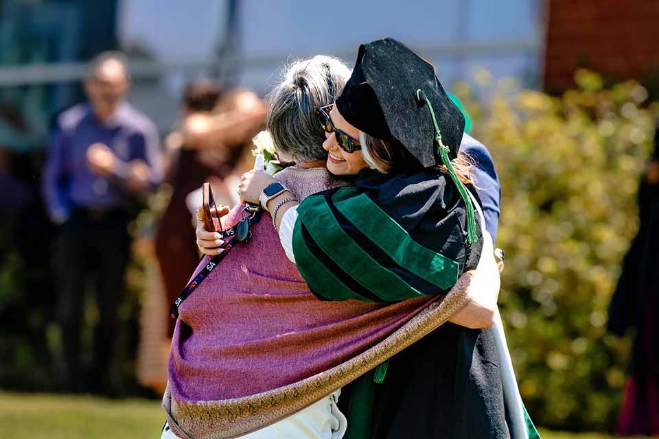 A graduate from the School of Medicine hugs a loved one after the precommencement ceremony on May 14, 2026. Photo by Sarah Conroy.
