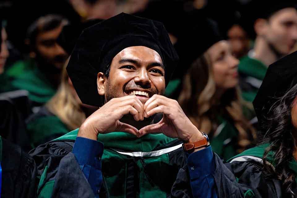 A graduate from the School of Medicine signs heart hands to his family during the precommencement ceremony on May 14, 2026. Photo by Sarah Conroy.

