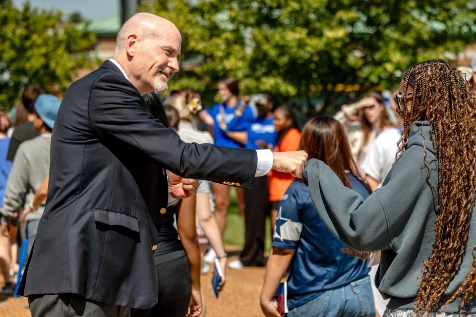 SLU President Edward Feser, Ph.D. fist-bumps a student following convocation on Tuesday, Aug. 18. Photo by Sarah Conroy.