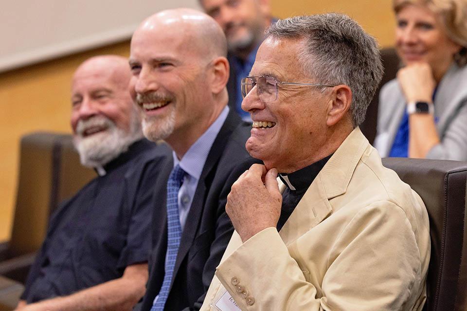 Frank Reale, S.J., right and President Edward Feser, Ph.D., center, and President Emeritus Lawrence Biondi, S.J, laugh during remarks before the installation of Reale’s portrait at San Ignacio Hall in SLU-Madrid on Sept. 22, 2026. Photo by Sarah Conroy.