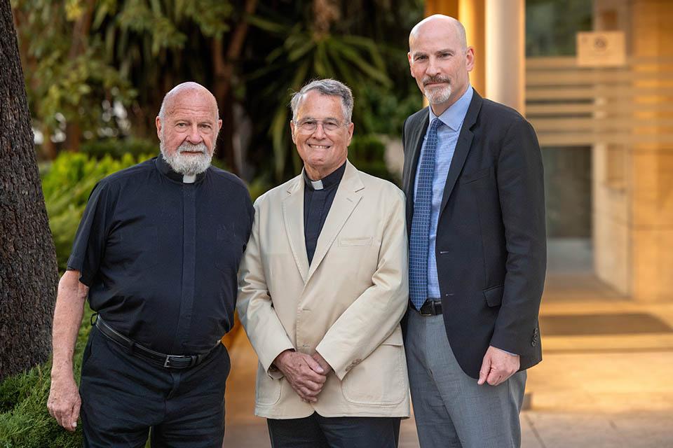 three men stand outside and pose for a picture