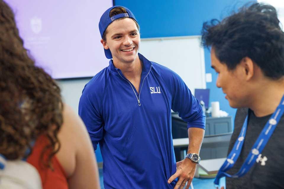 Actor dressed in SLU apparel chats with students in a classroom