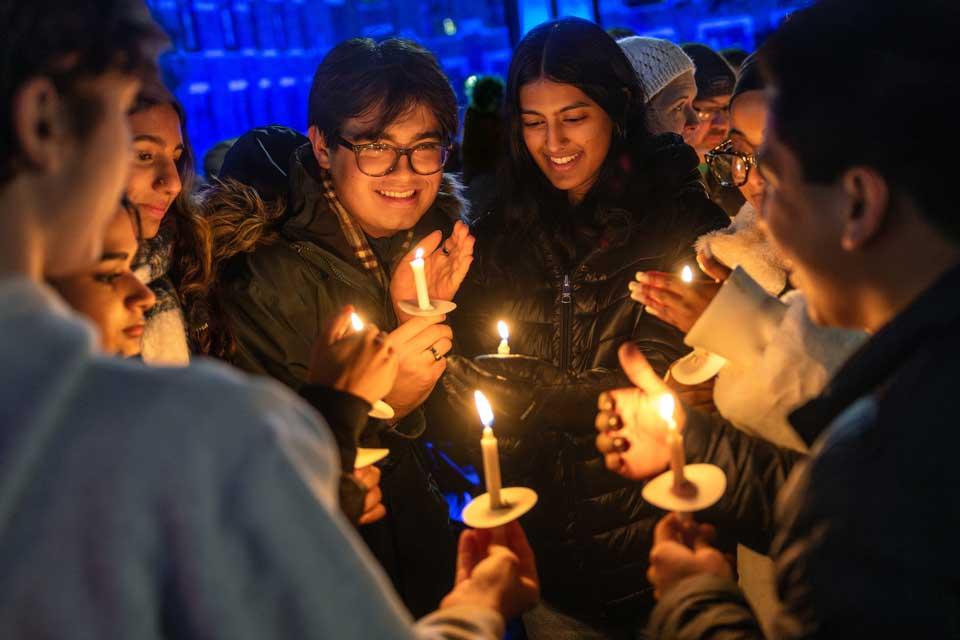 Students crowded together holding lit candles at night.