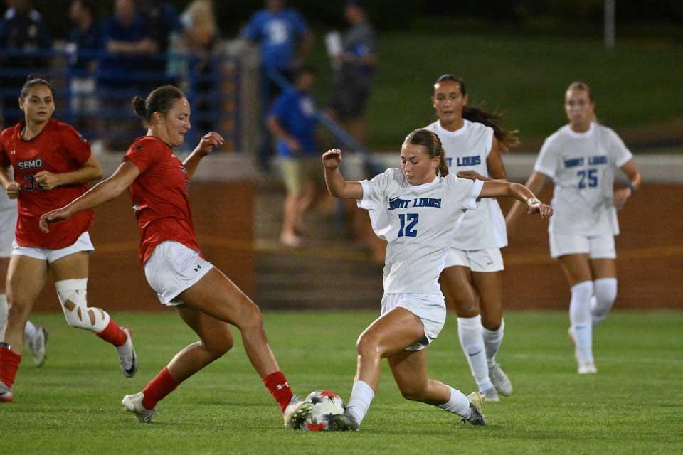 Action shot of two female soccer players during a night game.
