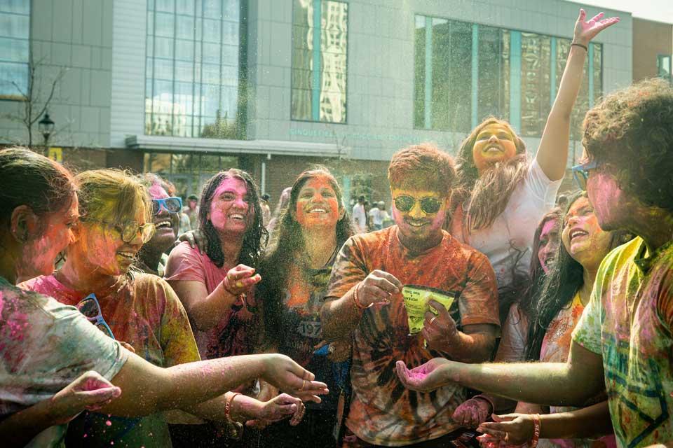 Students crowded together covered in brightly colored powder.