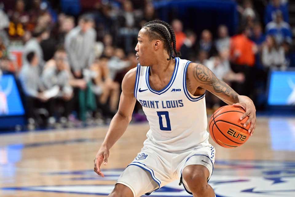 A SLU male basketball player dribbles up with the ball.