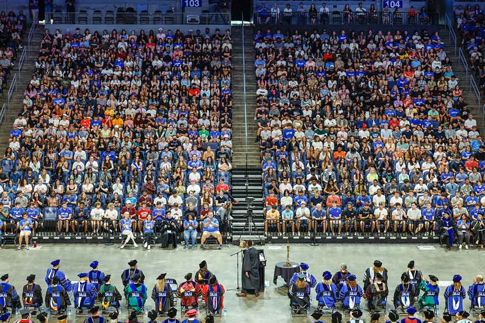 Students in arena seating seen from a distance listening to a speaker at SLU's convocation ceremony