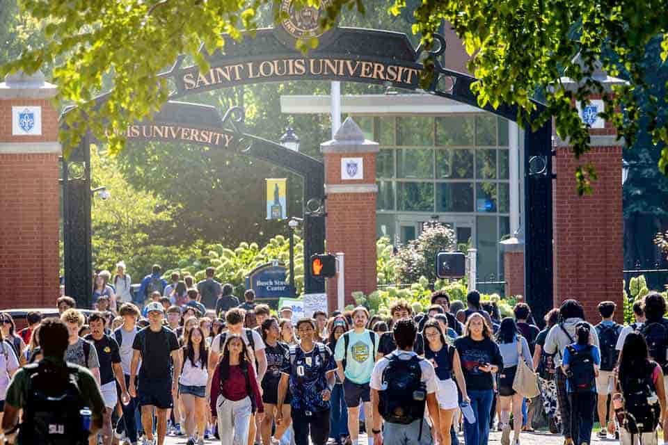 Honors and Rankings A large group of students walk under the Grand pedestrian arch.