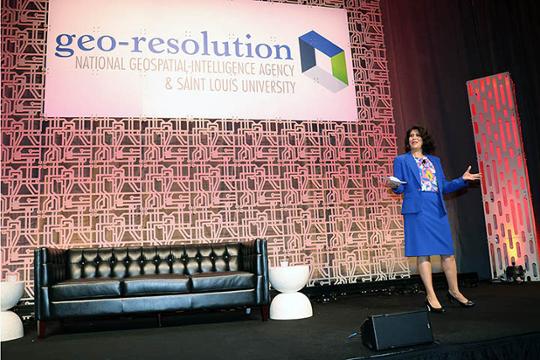 Nadine Alameh, Ph.D. inaugural executive director of the Taylor Geospatial Institute addresses crowd from stage at Geospatial Conference 2023