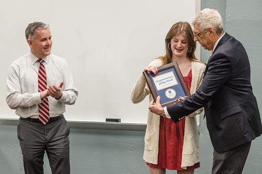 Gabby Chiodo accepts a Truman Scholar plaque from Dr. Pestello with Provost Lewis standing behind Chiodo