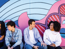 Four SLU students chatting in front of a painted mural