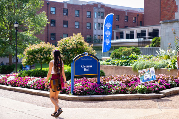 Student walking in front of Clemmon's Hall on SLU's campus