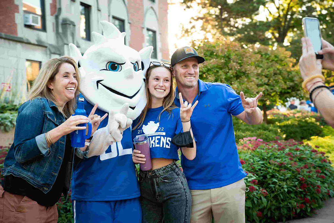 A family poses for a photo with the Billiken on homecoming weekend