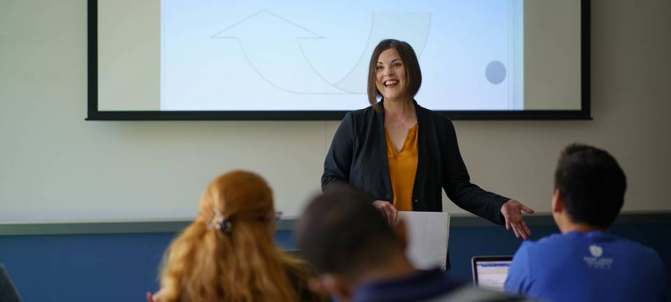 Professor teaching in front of projector in class