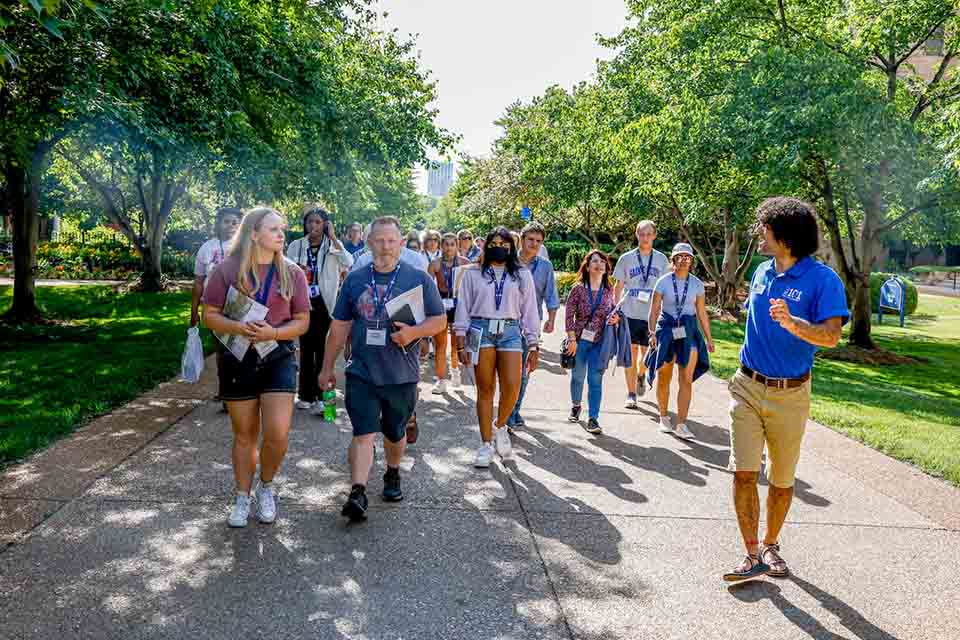 Students and famiies walking across campus on a tour led by a SLU101 leader