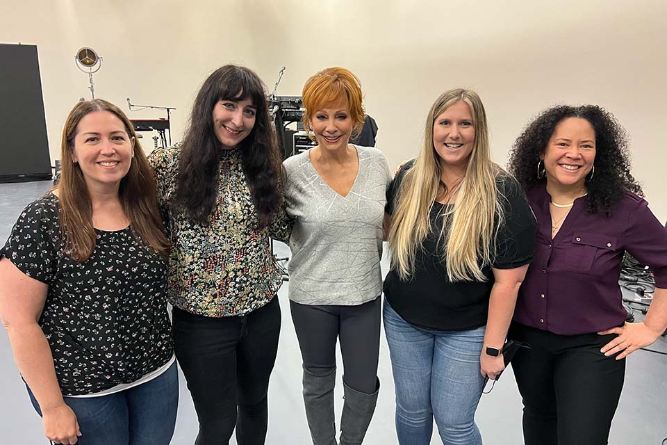 A group of four people pose for a photo with Reba McEntire.