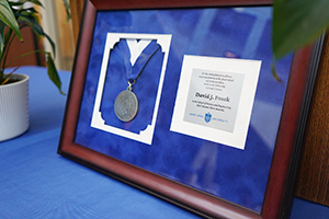 A medal framed alongside a plaque that says 