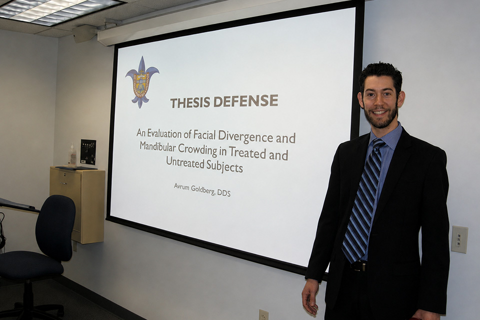 Avi Goldberg stands in front of a projector screen during a presentation in class.