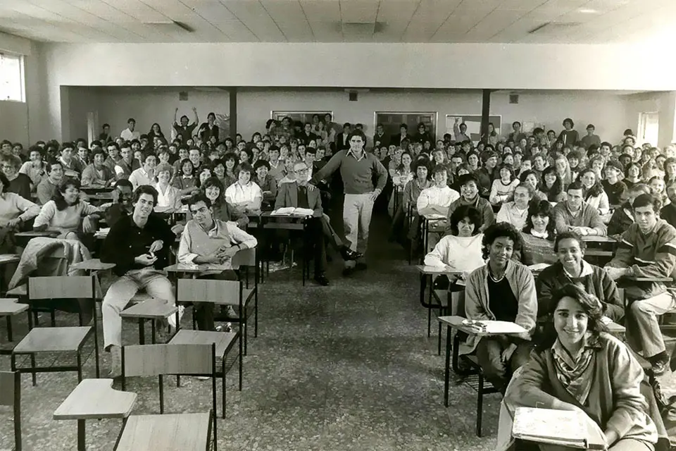 A group of students pose for a photo in a classroom in this black and white image.