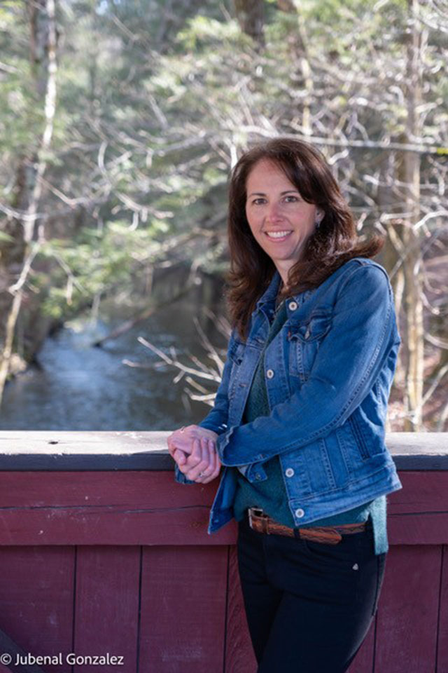 A woman poses for a photo against a backdrop.