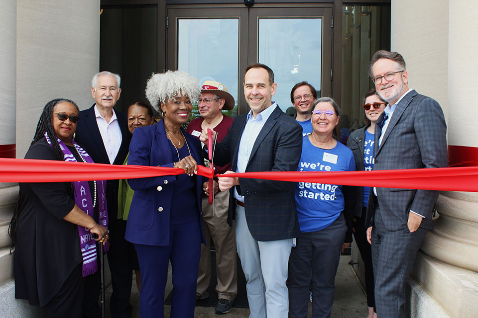Exhibit Opening A group of Missouri History Museum staff and partners pose for a photo cutting a large ribbon.