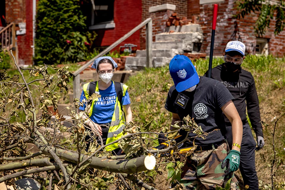 A few people clean up tree limbs outside.