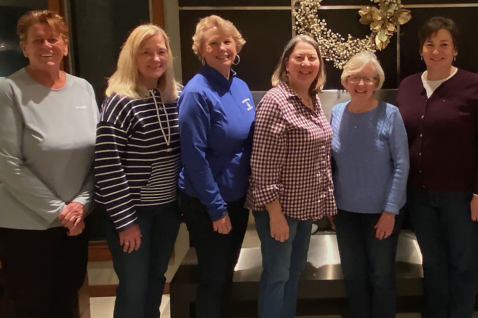 Volleyball Alumni A group of women pose for a photo together in a living room.