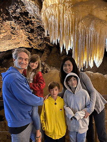 Travis Hoffstetter (A&S ‘05), poses for a photo with his family inside a cave.