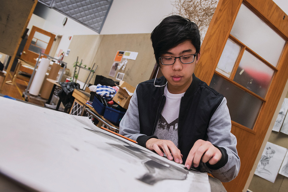 A student works on a drawing in a classroom studio.